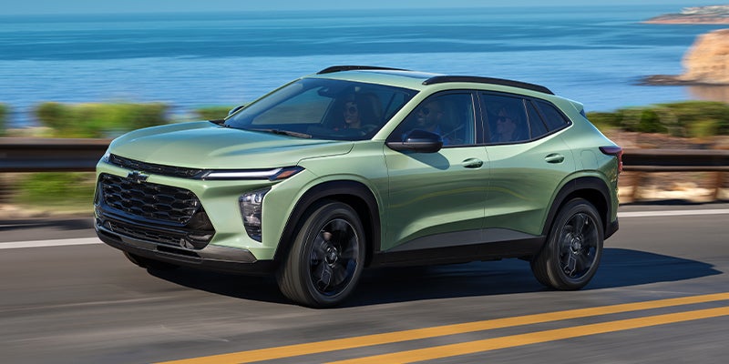 Green 2024 Chevrolet Trax driving down a coastal highway